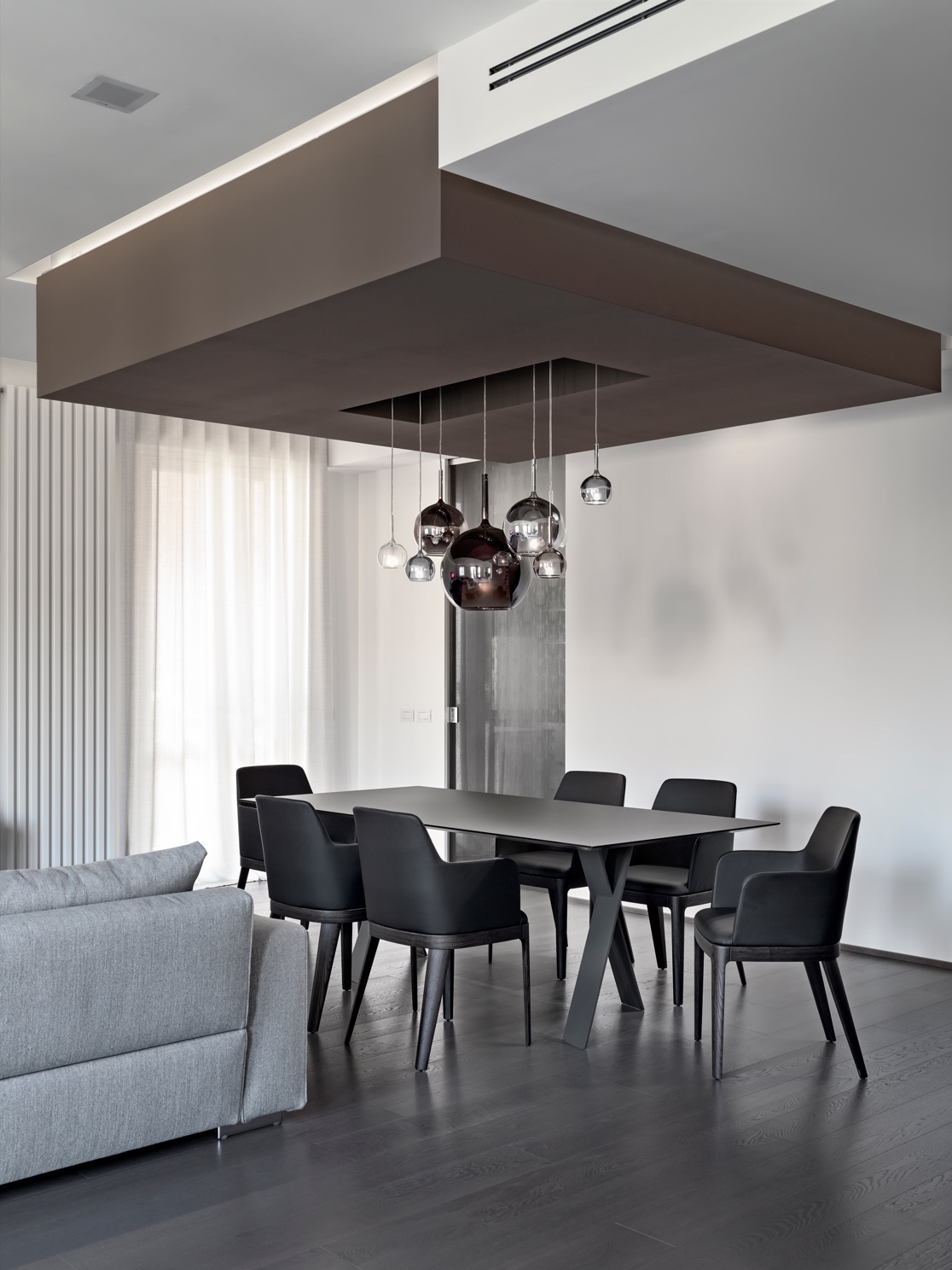 Open-plan dining and living area in a Best World residence with sculptural pendant lighting and a black dining table
