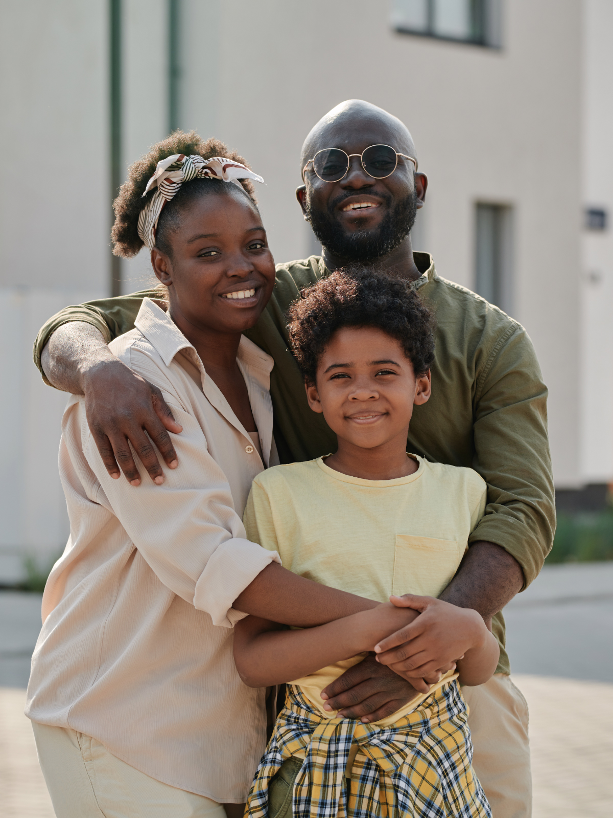 Family of three smiling in front of a Best World home