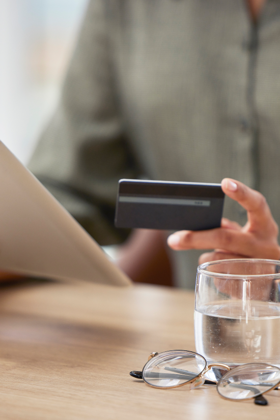 Hands holding eyeglasses and a phone over financial paperwork